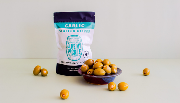 Garlic Stuffed Olives by in teal and white package with golden olives displayed in purple bowl