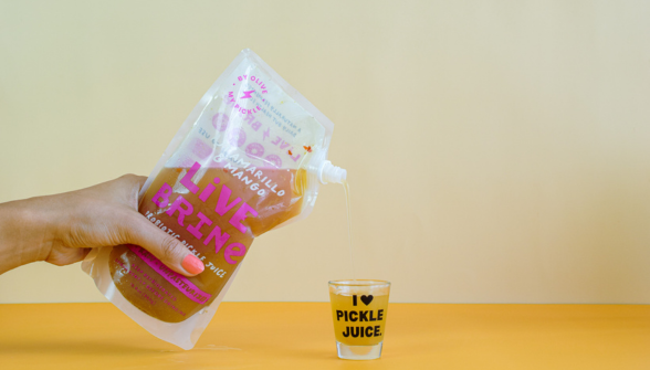 Pickle juice product held in hand with I Love Pickle Juice label on yellow background